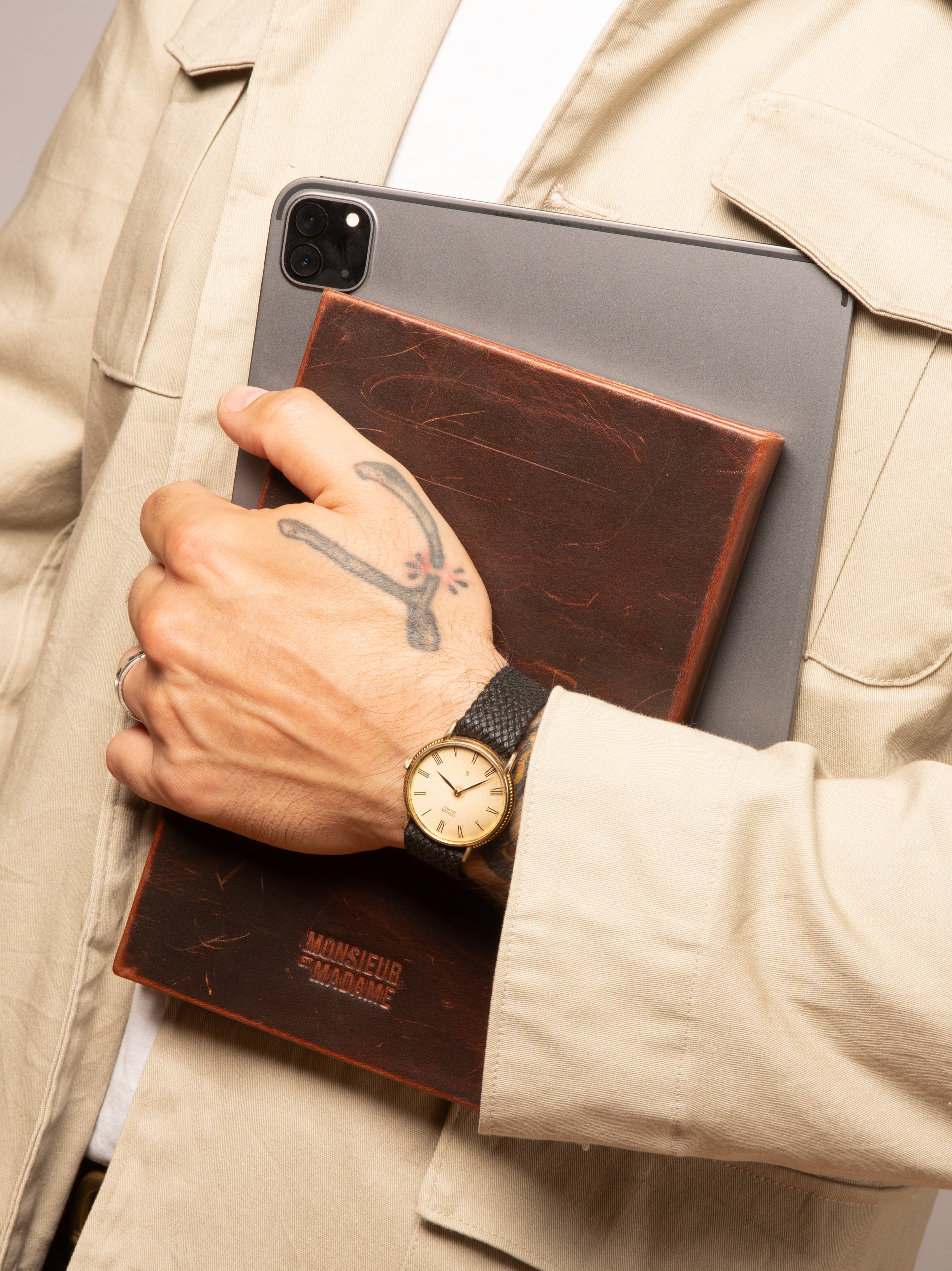 Cognac leather notebook with pull-up patina, carried against a tablet—lifestyle detail.