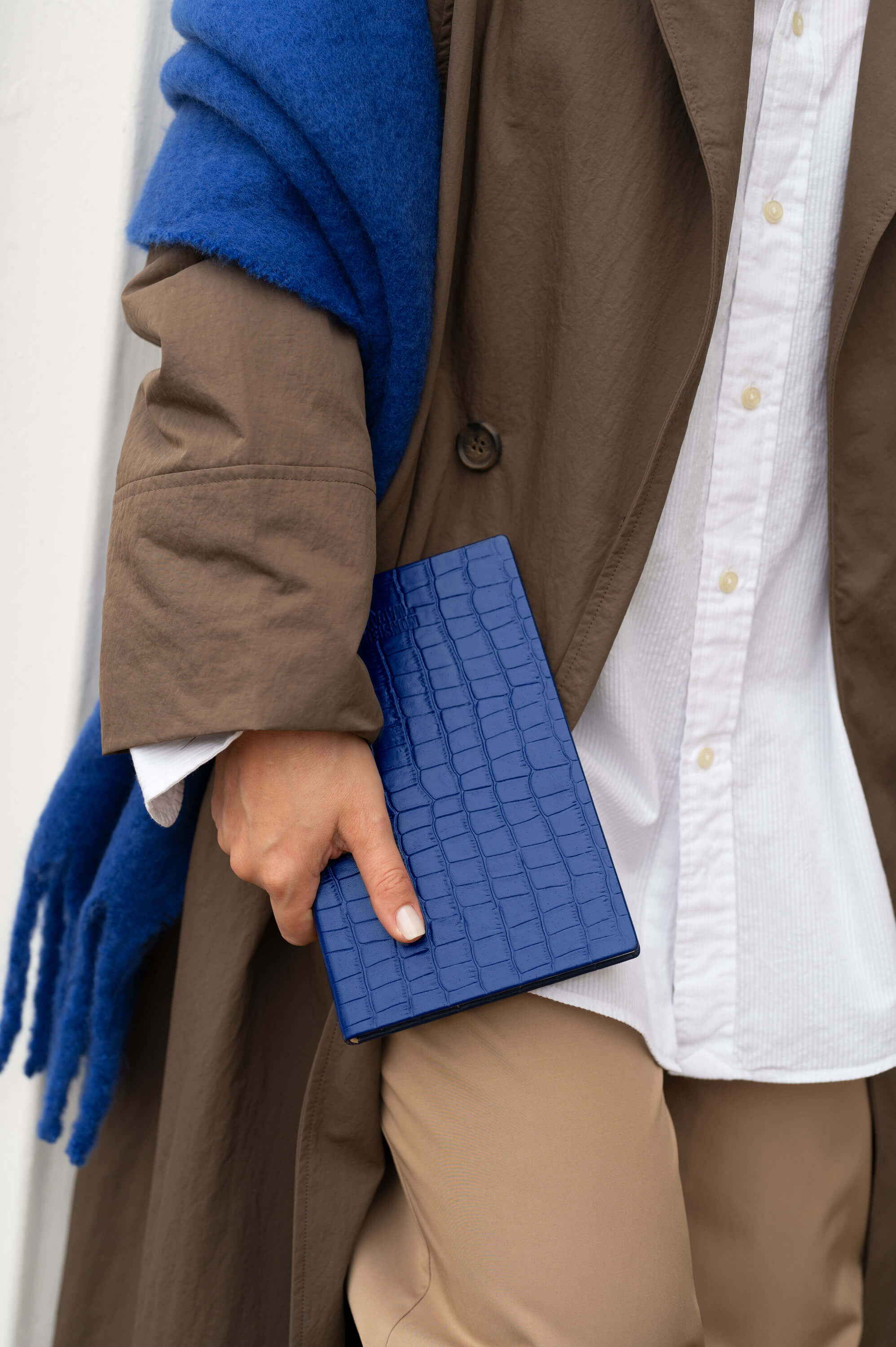 Lifestyle: Éclipse blue croc-embossed leather notebook carried under arm.