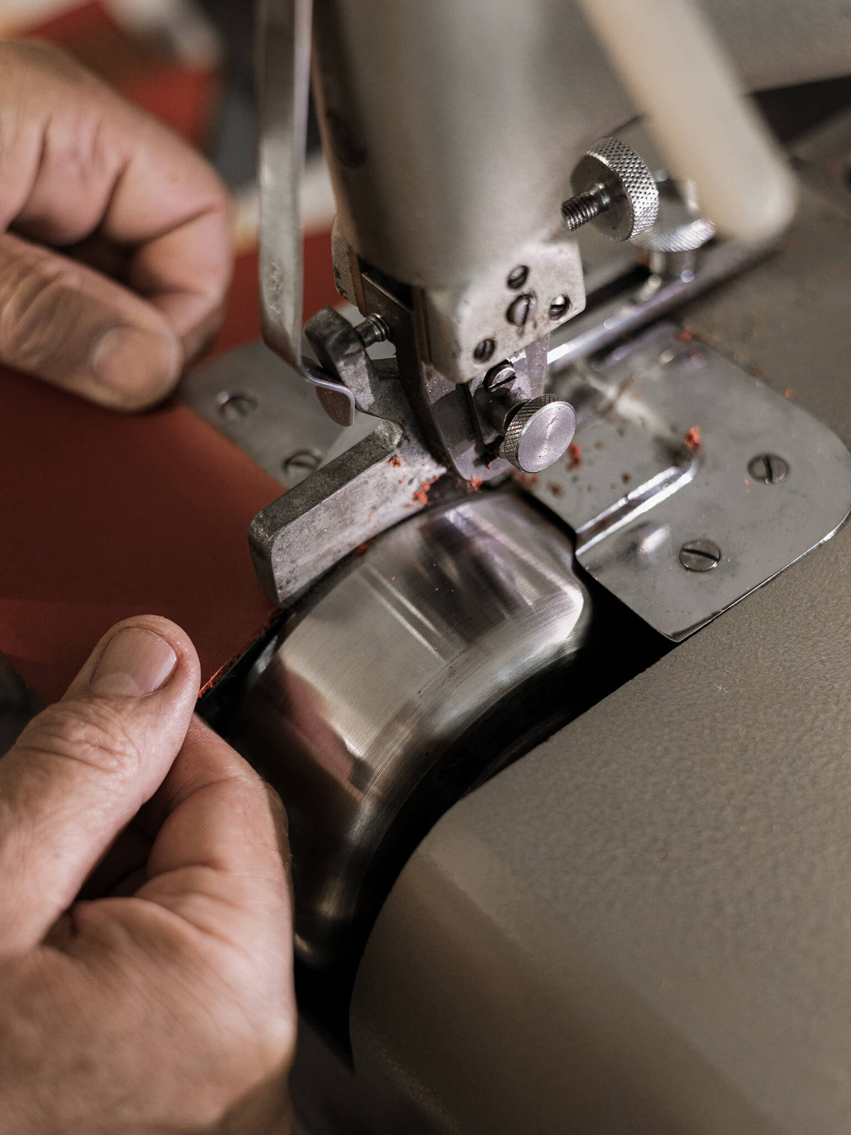 Close-up of a sewing machine needle and presser foot with hands adjusting the machine.